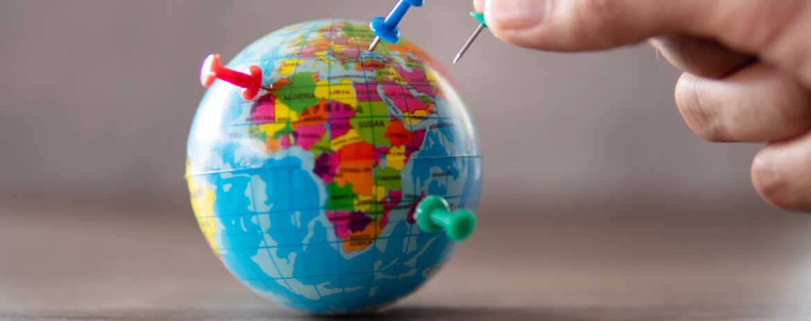 Image en gros plan d'une main plaçant des épingles sur le globe terrestre. Destination de voyage, concept de vacances planifiées.