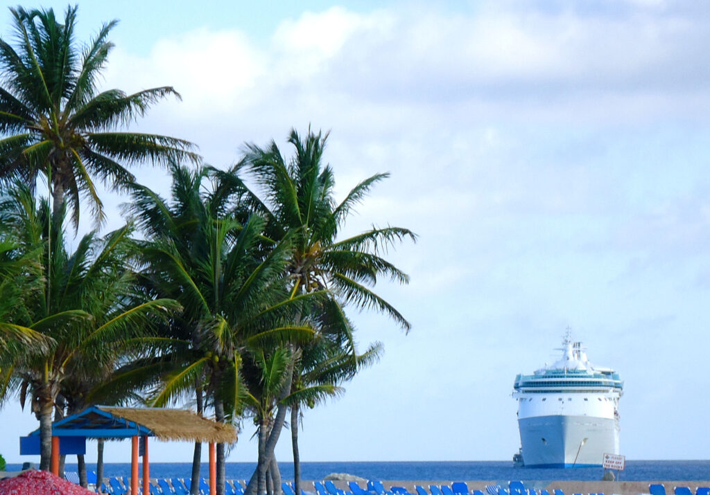 bateau de croisière ancré en mer au large de la côte caribéenne avec un palmier et la plage en avant plan